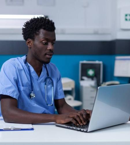 Nursing student in a clinic working on a laptop.