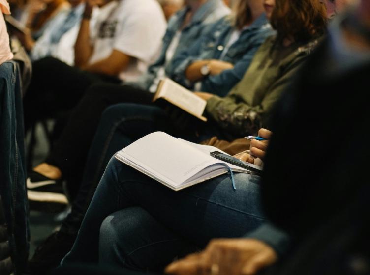 College students sitting in a large lecture class taking notes